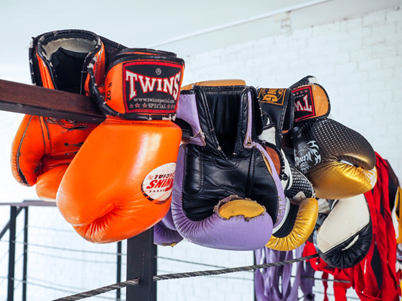 Boxing gloves sitting on the ropes of a boxing ring