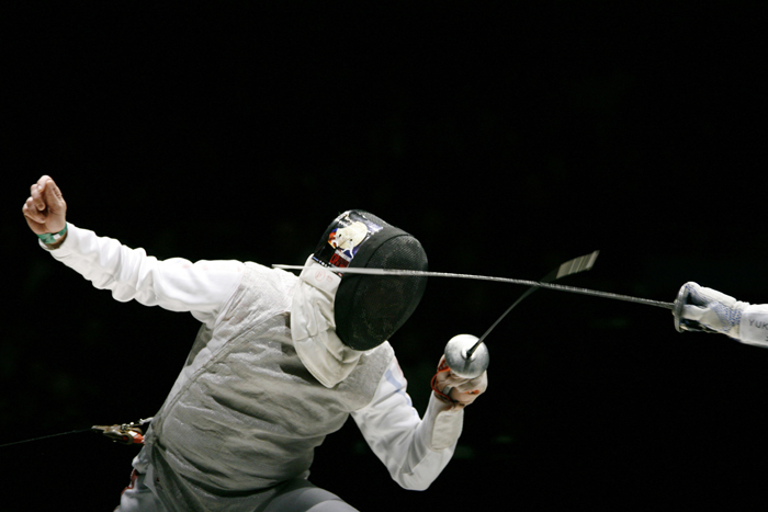 A fencer dodging a strike during a competition