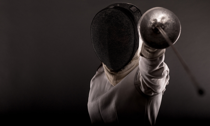 This is a photograph of a fencer aiming his sword at the camera