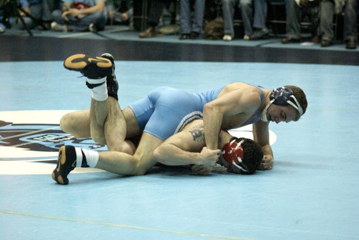 Folkstyle wrestling competition, with two wrestler on the ground fighting for position