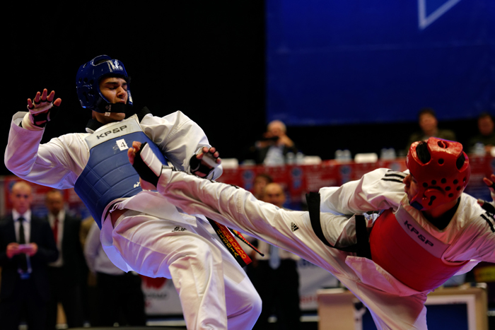 Taekwondo match taking place with a fighter landing a kick on his opponent