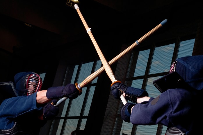 Kendo students sparring in traditional uniform with wooden swords