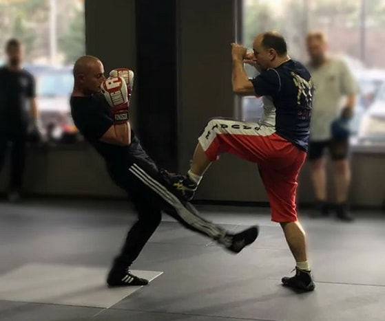 Two savate practitioners demonstrating kicks to a class of students